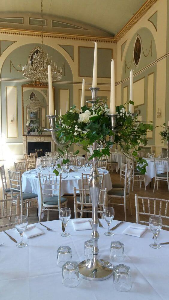 Tall candlestick with cream flowers and greenery at Sutton Bonnington Hall